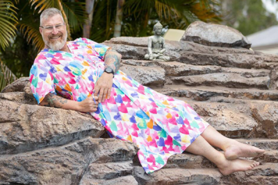 Graham Winbank, NUM Day Procedure Unit at Caboolture Hospital lounging on rocks in one of his dresses
