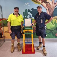 TPCH carpenters Paul Barber and Paul Keegan standing next to the paediatric chair that they built