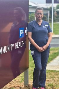 Clinical nurse Paula standing in front of Community Health sign 