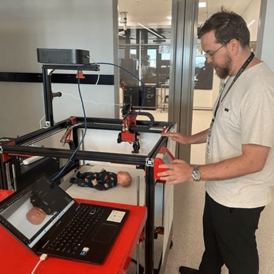 male student operating a large 3D printer that has a camera mounted on it as a mock photogrammetry rig