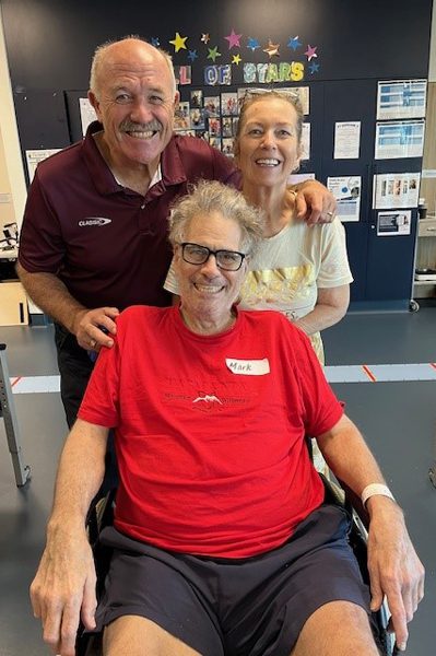 Wally Lewis visiting staff and patients at STARS rehabilitation gym, including patient Mark.
