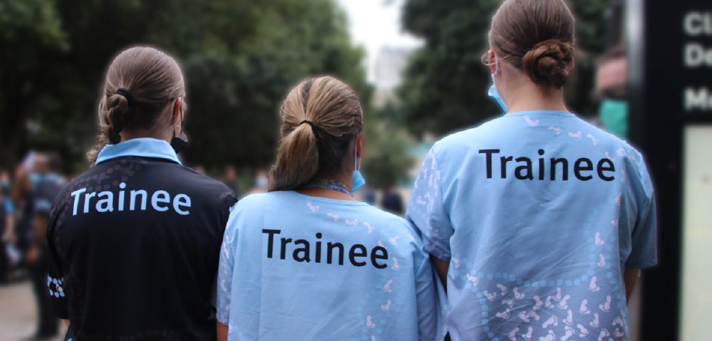 Three student trainees with their backs to the camera.